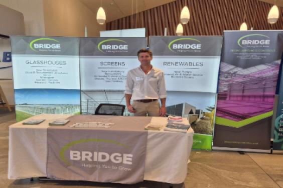 A man standing behind a Bridge Greenhouses trade stall 